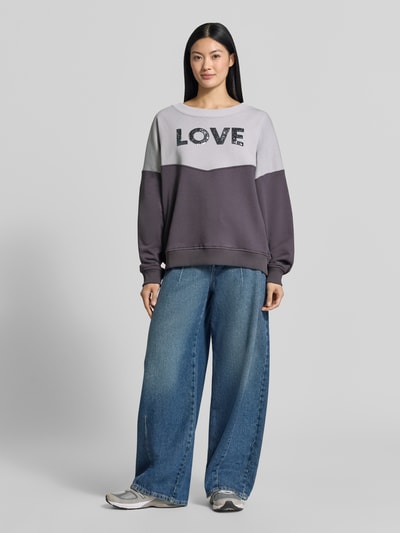 Frauenmodel trägt Oversized Sweatshirt aus reiner Baumwolle von miss goodlife in Grau mit Paillettenbesatz, gerippten Abschlüssen, Ganzkörperansicht von vorne.