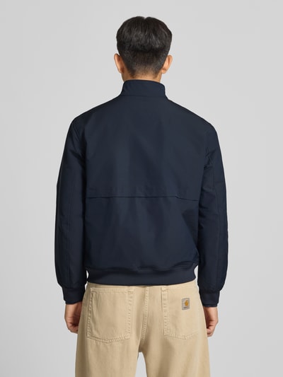 Männermodel trägt Regular Fit Jacke mit Logo-Stitching Modell 'HARRINGTON' von Superdry in Dunkelblau, Ganzkörperansicht Rückansicht. Elastischer Material-Mix, Stehkragen, Reißverschluss, Herren Jacke.
