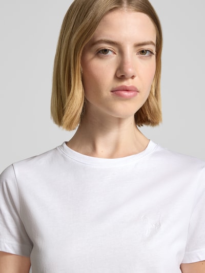Frauenmodel trägt T-Shirt mit Rundhalsausschnitt und Motiv-Stitching von JOOP! aus Reiner Baumwolle, Gerader-Schnitt, Nahaufnahme Oberkörper.
