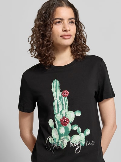 Frauenmodel trägt Damen T-Shirt von Only, Modell 'KITA', Optik: Unifarben schwarz, Motiv-Print mit Pailletten, Kurzarm, Rundhals, Jersey aus reiner Baumwolle, Nahaufnahme Oberkörper.