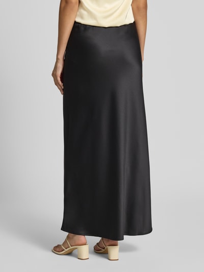 Frauenmodel trägt Ausgestellter Maxi-Rock mit elastischem Bund Modell 'MERLE' von VERO MODA in Schwarz, seidige Textur, Ganzkörperansicht Rückansicht. Damen Maxi-Rock von VERO MODA.