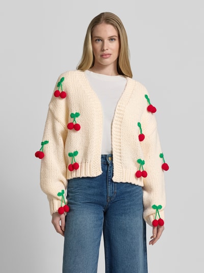 Frauenmodel trägt Oversized Strickjacke mit Zier-Applikationen von Apricot in Creme, Grobstrick, offene Vorderseite, Ganzkörperansicht von vorne.