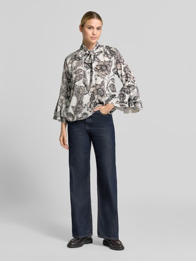 Vrouwenmodel draagt Regular Fit Bluse met Sierstrik van monari, dames blouse met all-over bloemenprint, 3/4-mouw, ruglengte maat 36: 61 cm, mouwlengte maat 36: 50 cm, overwegend wit en zwart met florale motieven, zachte en vloeiende textuur, geheelbeeld vooraanzicht.