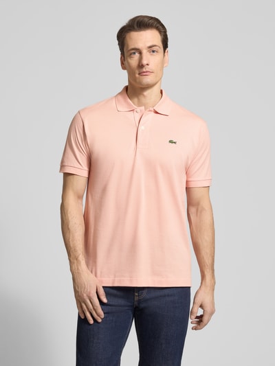 Männermodel trägt Regular Fit Poloshirt aus reiner Baumwolle von Lacoste in Optik: Unifarben mit Logo-Stitching, Polokragen, Kurzarm, Piqué-Struktur, Ganzkörperansicht von vorne.