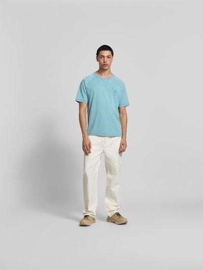 Männermodel trägt Regular Fit T-Shirt mit Logo-Print von MAISON KITSUNÉ aus reiner Bio-Baumwolle in Hellblau, Ganzkörperansicht von vorne.