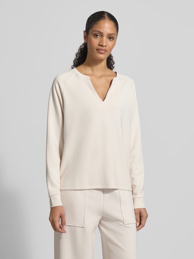 Modelka nosi Relaxed Fit Sweatshirt mit Stretch-Anteil von Christian Berg Woman, jasny kremowy kolor, V-dekolt, długie rękawy, elastyczna mieszanka materiałów z dodatkiem modalu, fason relaxed fit, damska bluza, widok całej sylwetki z przodu.