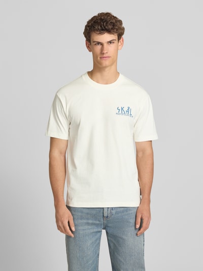 Männermodel trägt Relaxed Fit T-Shirt aus reiner Baumwolle von Marc O'Polo Denim, Optik: Unifarben, Passform: Relaxed-Fit, Applikation: Label-Print, Rundhals, Ärmelform: Kurzarm, Material: Reine Baumwolle, helle Farben, glatte Struktur, Ganzkörperansicht von vorne.