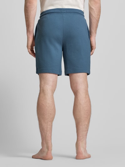 Männermodel trägt Regular Fit Sweatshorts aus Baumwoll-Mix Modell 'AUSTIN' von HUGO, unifarben, Piqué-Struktur, Ganzkörperansicht Rückansicht.