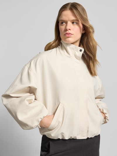 Vrouwenmodel draagt Bomberjacke met Stehkragen und Logo-Print van PUMA in crème, los model, met steekzakken, ballonmouwen, drukknoop- en ritssluiting, logoprint, opstaande kraag, schouderbreedte 56 cm, borstwijdte 55 cm, mouwlengte 50 cm, ruglengte 54 cm, vooraanzicht bovenlichaam.