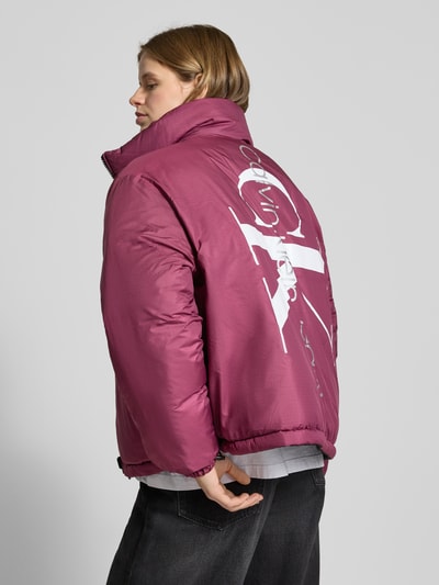 Modelka nosi 'Jacke mit Logo-Print' od Calvin Klein Jeans, prosty krój, jednolity kolor, nadruk z logo, elastyczne mankiety, zdjęcie całej sylwetki z tyłu. Długość pleców w rozmiarze M: 66 cm, szerokość ramion w rozmiarze M: 63 cm, szerokość klatki piersiowej w rozmiarze M: 60 cm, długość rękawa w rozmiarze M: 63 cm.