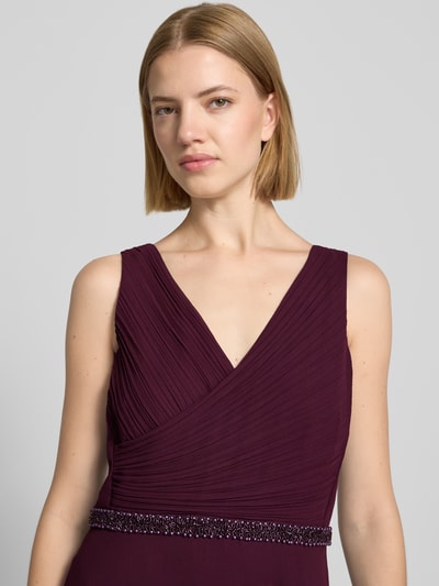 Frauenmodel trägt Fit and Flare Abendkleid mit Perlenstickerei von Vera Mont in dunklem Weinrot, strukturierte Oberfläche, Nahaufnahme Oberkörper.