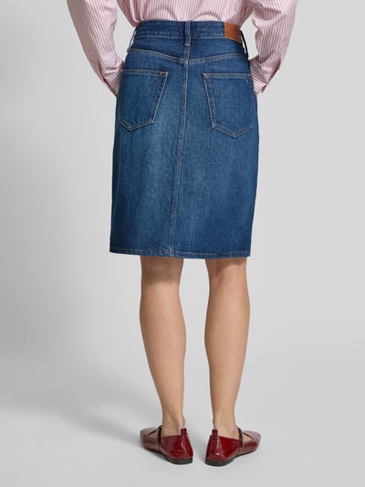 Frauenmodel trägt Körpernaher Jeansrock aus reiner Baumwolle von Tommy Hilfiger, Optik: Unifarben, Passform: Körpernah, Länge: Knielang, Label-Patch, Logo-Detail, Nieten, Gürtelschlaufen, Verschluss: Knopf und Reißverschluss, 5-Pocket-Design, Materialverarbeitung: Denim, Material: Reine Baumwolle, Ganzkörperansicht Rückansicht.