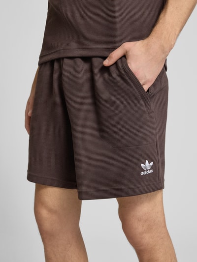 Männermodel trägt Regular Fit Sweatshorts mit Baumwoll-Anteil von adidas Originals, Optik: Unifarben, Waffelstruktur, Logo-Stitching, Bundabschluss: Elastisch, Taschen: seitliche Eingrifftaschen, Nahaufnahme Oberkörper bis Oberschenkel.