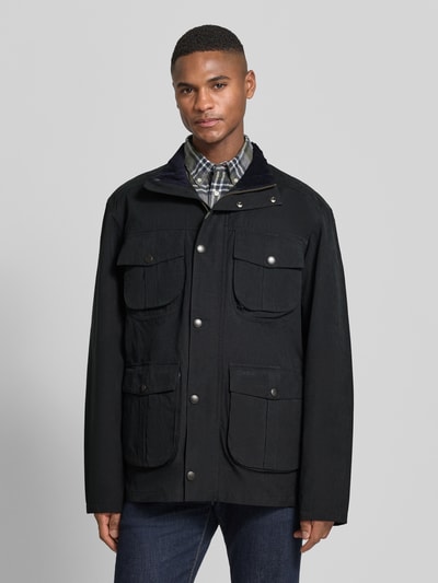 Mężczyznamodel nosi Regular Fit Jacke aus Baumwoll-Mix Modell 'SANDERLING' von Barbour, czarny, krój regular fit, mieszanka bawełny, nakładane kieszenie, stójka, zamek błyskawiczny dwustronny, naszywka z logo, napis z logo, pas w talii, długi rękaw, proste zakończenie rękawów, widok całej sylwetki z przodu.