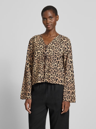 Modelka nosi Bluse mit Kimonoärmeln und Schnürung Modell 'PRISILLA' von Vila, beżowo-czarny wzór panterki, krój regular fit, LENZING™ ECOVERO™, dekolt w serek, długość pleców 38 cm, długość rękawa 63 cm, widok całej sylwetki z przodu.