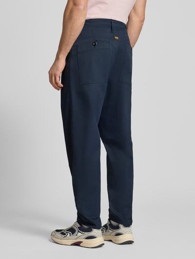 Männermodel trägt Straight Fit Chino mit Bundfalten von G-Star Raw in Dunkelblau, elastischer Material-Mix, Ganzkörperansicht Rückansicht