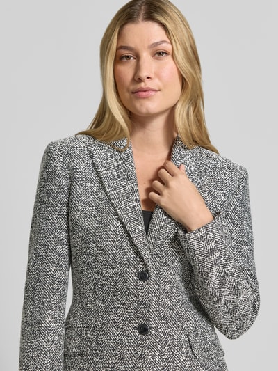 Frauenmodel trägt Regular Fit Longblazer mit 2-Knopf-Verschluss Modell 'Asmalla' von HUGO, grau-schwarzes Muster, Damen Longblazer, Nahaufnahme Oberkörper.