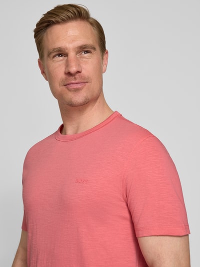 Männermodel trägt Regular Fit T-Shirt aus reiner Baumwolle Modell 'TEGOOD' von BOSS Orange in Optik: Unifarben, Logo-Detail, Rundhals, Kurzarm, Nahaufnahme Oberkörper.