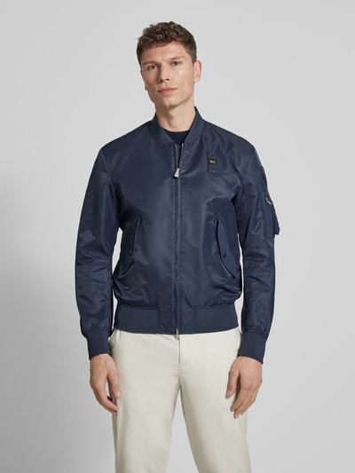 Männermodel trägt Jacke mit Zweiwege-Reißverschluss Modell 'Rocky' von Blauer Usa in Dunkelblau, Regular Fit, Stehkragen, Ganzkörperansicht von vorne.