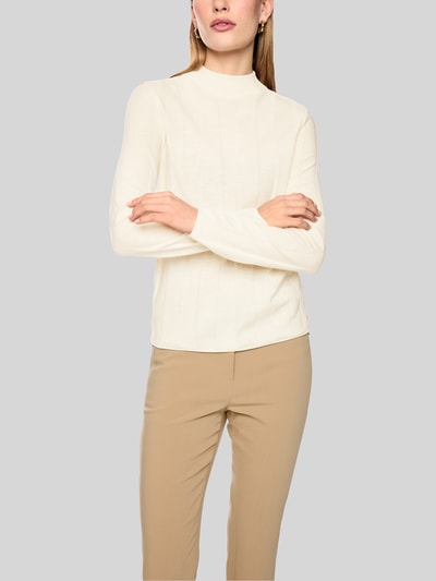 Frauenmodel trägt Strickpullover aus Schurwolle-Mix mit Stehkragen von Marc Cain, Slim Fit, creme, weiche Textur, Nahaufnahme Oberkörper.