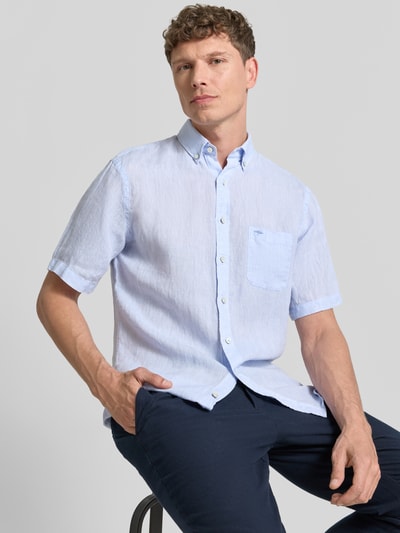Männermodel trägt Regular Fit Leinenhemd mit Button-Down-Kragen von Fynch-Hatton in Hellblau, reine Leinenstruktur, Brusttasche, Nahaufnahme Oberkörper.