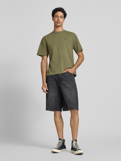 Männermodel trägt T-Shirt mit Label-Patch und Rundhalsausschnitt von REVIEW, Reine Baumwolle, Boxy-Fit, Rückenlänge 66 cm, Ganzkörperansicht von vorne.