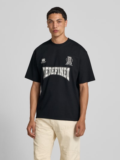 Männermodel trägt T-Shirt mit Statement-Print und Rundhalsausschnitt von Redefined Rebel aus Baumwoll-Mix im Relaxed-Fit, Ganzkörperansicht von vorne. Modell Bruno, Rückenlänge bei Größe M 70 cm.