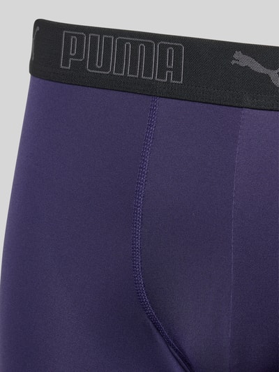Männermodel trägt Slim Fit Trunk mit Logo-Stitching von PUMA in Lila, elastischer Bund, glatte Oberfläche, Nahaufnahme Oberkörper.