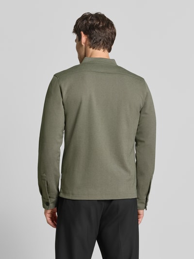Männermodel trägt Slim Fit Sweatjacke mit Stehkragen von Lindbergh, Mieszanka materiałów z dodatkiem streczu, zamek błyskawiczny, wpuszczane kieszenie, długość tyłu w rozmiarze M: 67 cm, długość rękawów w rozmiarze M: 66 cm, kolor oliwkowy, krój slim fit, całkowity widok z tyłu.