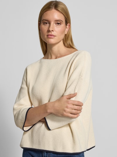 Frauenmodel trägt Strickpullover mit 3/4-Ärmel von comma aus reiner Baumwolle in Creme mit dunkel abgesetztem Saum, lockerer Schnitt, U-Boot-Ausschnitt, Nahaufnahme Oberkörper.