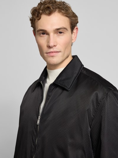 Männermodel trägt Regular Fit Blouson mit Logo-Muster Modell 'H-CRESTELL' von BOSS, Nahaufnahme Oberkörper, Optik: Allover-Muster, Umlegekragen, Reißverschluss, Label-Applikation aus Metall, langarm mit elastischem Ärmelabschluss, Tunnelzug innen, seitliche Eingrifftaschen, Napoleontasche.