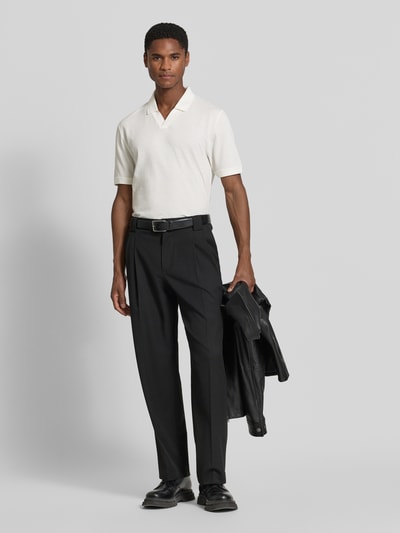 Männermodel trägt Regular Fit Poloshirt aus Baumwoll-Mix von s.Oliver RED LABEL in Weiß, schwarze Hose, Ganzkörperansicht von vorne.