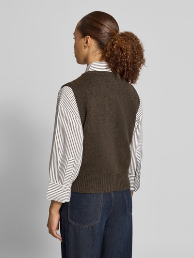 Frauenmodel trägt Regular Fit Strickweste aus Woll-Mix von Christian Berg in Dunkelbraun über gestreifter Bluse, gerippte Abschlüsse, ärmellos, Rückenlänge 45 cm, Ganzkörperansicht Rückansicht.