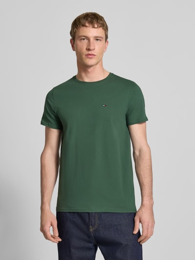 Männermodel trägt Regular Fit T-Shirt aus reiner Baumwolle von Tommy Jeans in Optik: Unifarben mit Logo-Stitching, Kurzarm, Ganzkörperansicht von vorne.