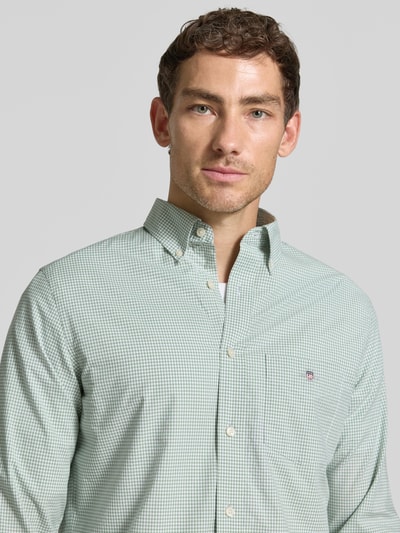 Männermodel trägt Regular Fit Freizeithemd aus reiner Baumwolle von GANT, feines grünes Karo, Nahaufnahme Oberkörper.
