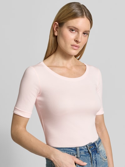 Frauenmodel trägt T-Shirt mit Rundhalsausschnitt und 1/2-Arm von Marc Cain in zartem Rosa, Slim Fit, glatte Textur, Nahaufnahme Oberkörper. Baumwoll-Elasthan-Mix, Rückenlänge 56 cm bei Größe 36.