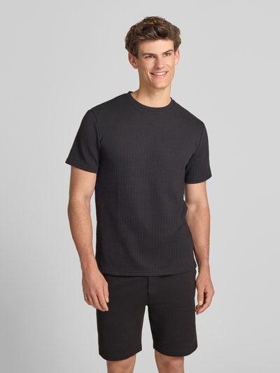 Männermodel trägt Regular Fit T-Shirt mit Viskose-Anteil Modell 'TREY' von Only & Sons in Optik: Unifarben, Struktur, Rundhals, Kurzarm, Ganzkörperansicht von vorne.