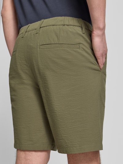 Mężczyzna nosi Regular Fit bermudy z mieszanki bawełny model 'KARL' od SELECTED HOMME, wzór w paski, faktura seersucker, kolor oliwkowy, wpuszczane i tylne kieszenie; efekt: wzór na całej powierzchni, wykończenie: mieszanka bawełny; całkowity widok z tyłu