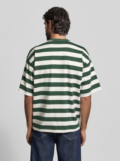 Männermodel trägt Relaxed Fit T-Shirt mit Logo-Stitching Modell 'Beam' von Woodbird aus reiner Baumwolle in Grün und Weiß, Rückenlänge bei Größe M 73 cm, Ganzkörperansicht Rückansicht.