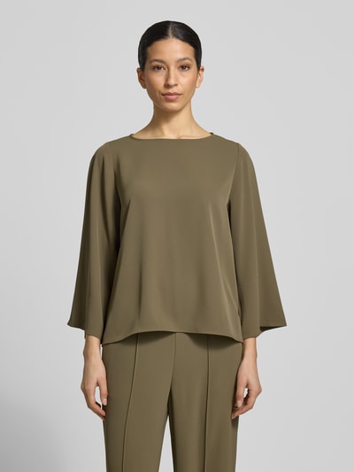 Vrouwenmodel draagt Relaxed Fit Bluse mit Rundhalsausschnitt van comma, elastische materiaalmix in olijfgroen, met lange mouwen, gladde structuur, ganzkörperansicht van voren. Ruglengte maat 36: 57 cm, mouwlengte maat 36: 51 cm.