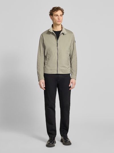 Männermodel trägt Jacke mit Stehkragen Modell 'Vicente' von JOOP! Collection in Regular-Fit, Reißverschluss, Eingrifftaschen, beige, Ganzkörperansicht von vorne. Rückenlänge 66 cm, Schulterbreite 46 cm, Brustweite 52 cm, Ärmellänge 67 cm.