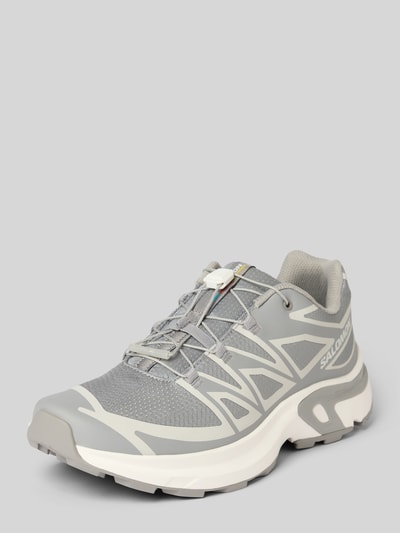 Produktfoto, grauer Sneaker mit profilierter Sohle Modell 'XT-EVR' von Salomon, abgerundete Spitze, Schnürung, Logo, weiße Akzente, strukturierte Mesh- und Synthetik-Oberfläche, sportliches Design