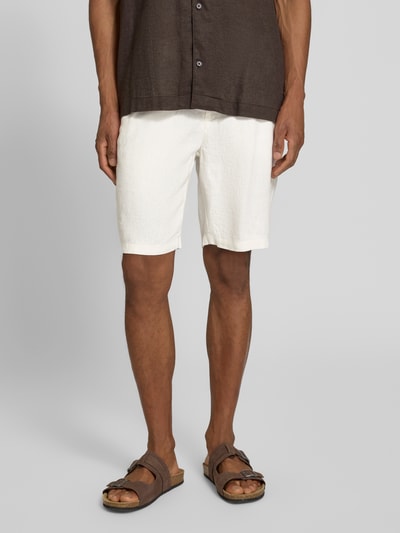 Męski model nosi Leinen Shorts mit Eingrifftaschen Modell 'PANDRUP' od Casual Friday, czyste len, krój straight fit, kolor biały, guzik i zamek, boczne kieszenie, kieszenie z tyłu, szerokość w rozmiarze M: 44 cm, długość wewnętrzna nogawki w rozmiarze M: 23 cm, pełny widok z przodu