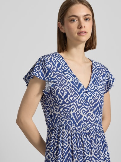 Frauenmodel trägt Tailliertes Freizeitkleid aus reiner Viskose Modell 'CLAUDETTE' von Only mit blau-weißem Allover-Muster, V-Ausschnitt, kurze Ärmel, Webware-Textur, Nahaufnahme Oberkörper.