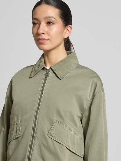 Modelka kobieca nosi Oversized Bomberjacke aus reiner Baumwolle von Marc O'Polo, efekt: jednolity kolor, krój oversized, zamek błyskawiczny, naszywka z logo, długi rękaw z mankietem, tunel u dołu, kieszenie z patką, splot twill, bawełna, zbliżenie na górną część ciała.