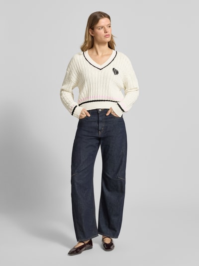 Frauenmodel trägt Strickpullover mit Zopfmuster und V-Ausschnitt Modell 'MAKI' von Noisy May, Baumwoll-Mix, Regular-Fit, Ganzkörperansicht von vorne.