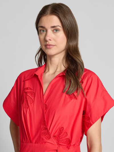 Frauenmodel trägt Jumpsuit in Wickel-Optik Modell 'TRACY' von SUNCOO PARIS aus Reine Baumwolle mit Lochstickerei in Rot, Nahaufnahme Oberkörper.