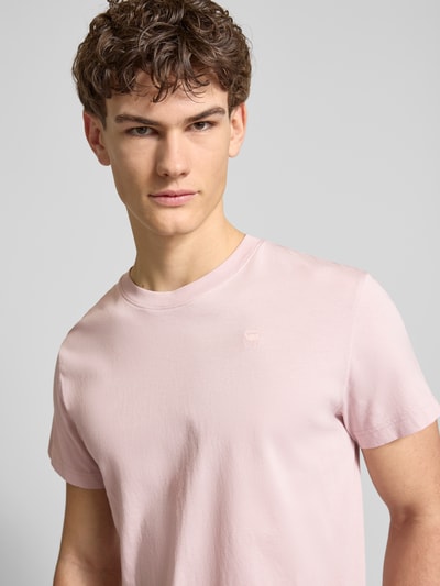 Męski model nosi T-Shirt aus Baumwolle von G-Star Raw, prosty krój, okrągły dekolt, wyhaftowane logo, jasnoróżowy, zbliżenie na górę ciała.