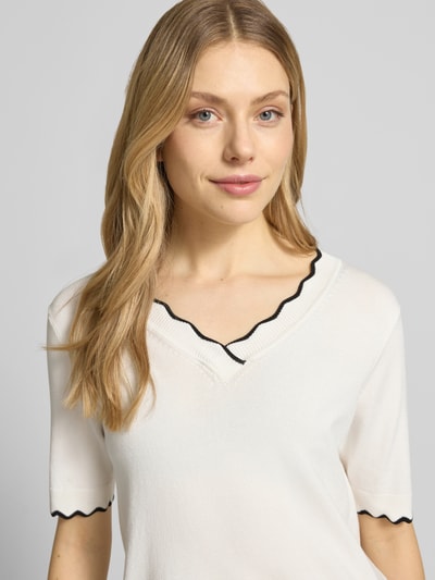 Frauenmodel trägt Strickshirt aus Viskose-Mix mit Kontraststreifen Modell 'MORLA' von B.Young in Weiß mit schwarzem Akzent, Regular-Fit, V-Ausschnitt, Damen, Nahaufnahme Oberkörper. Rückenlänge bei Größe S: 52 cm.