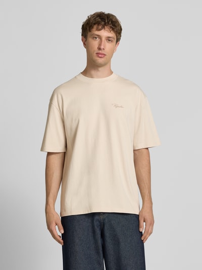 Męski model nosi Oversized T-Shirt mit Label-Stitching od Pegador, kremowy kolor, czysta bawełna, okrągły dekolt, oversized, widok całej sylwetki z przodu, długość tyłu w rozmiarze M: 70 cm.